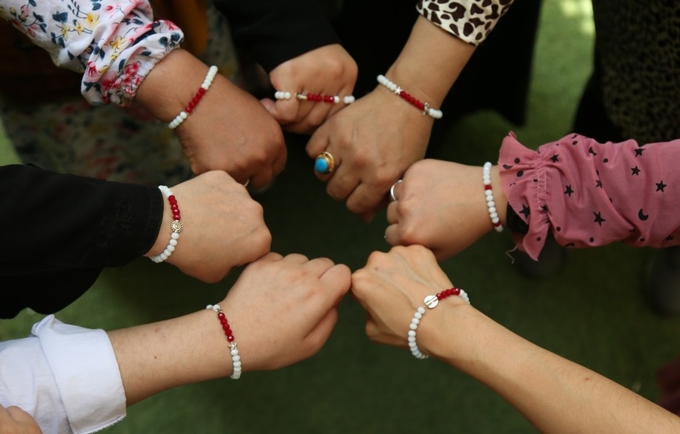Girls show off their Menstruation Bracelets, made out of 28 beads, 5 of which are red.